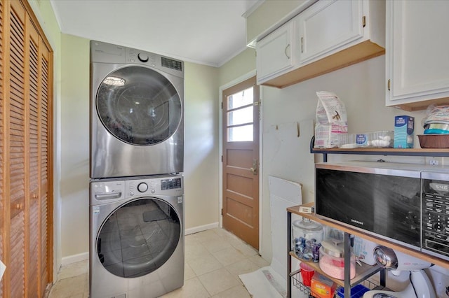 3935 Orr Dr, North Branch, MI 48461 - laundry room featuring stacked washing machine and dryer, cabinet space, baseboards, light tile patterned floors, and crown molding