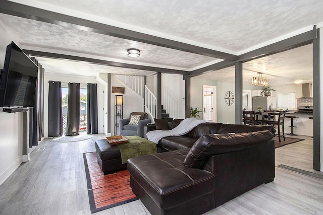 living room featuring stairs, beam ceiling, a chandelier, light wood-style floors, and baseboards