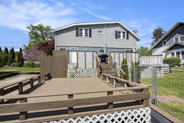 rear view of house featuring fence and a deck