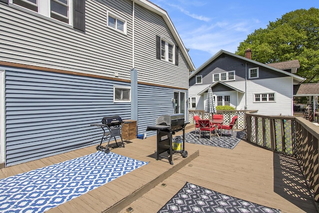 wooden terrace featuring area for grilling and outdoor dining space