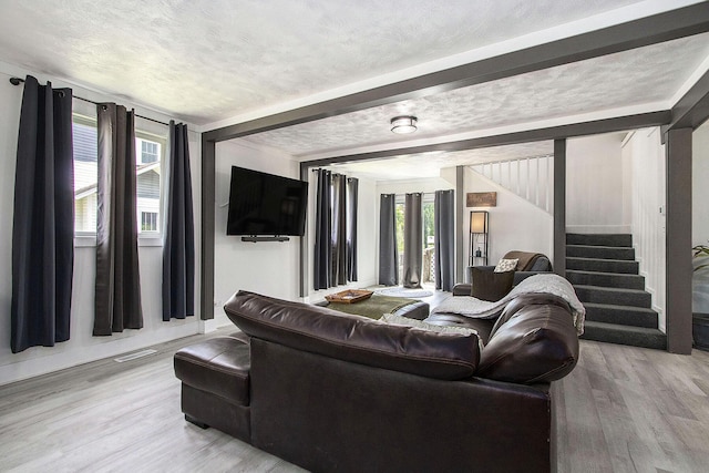 living area with stairway, light wood-style floors, and a textured ceiling