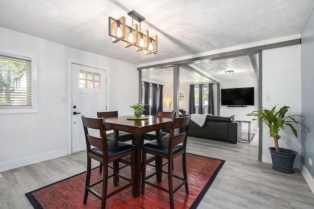 dining area with baseboards, light wood-style floors, and a chandelier