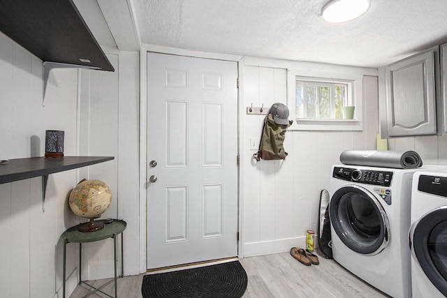 clothes washing area featuring a textured ceiling, light wood-style flooring, baseboards, and washer and clothes dryer