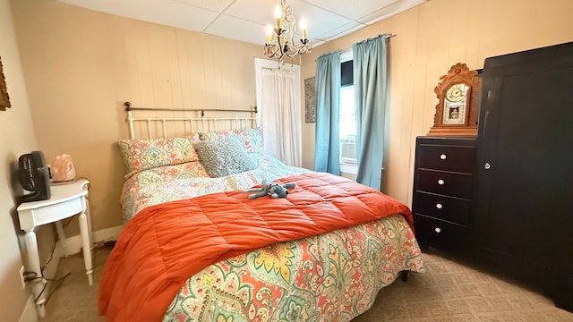 carpeted bedroom with a chandelier and a drop ceiling