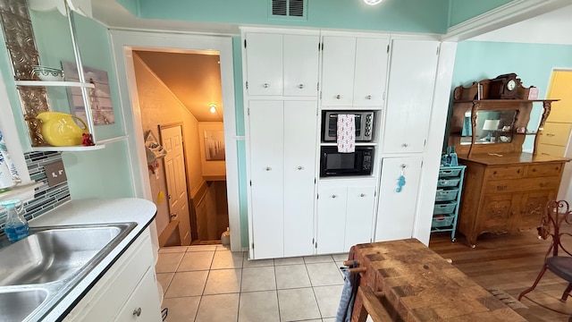 kitchen featuring a sink, white cabinetry, black microwave, open shelves, and stainless steel microwave