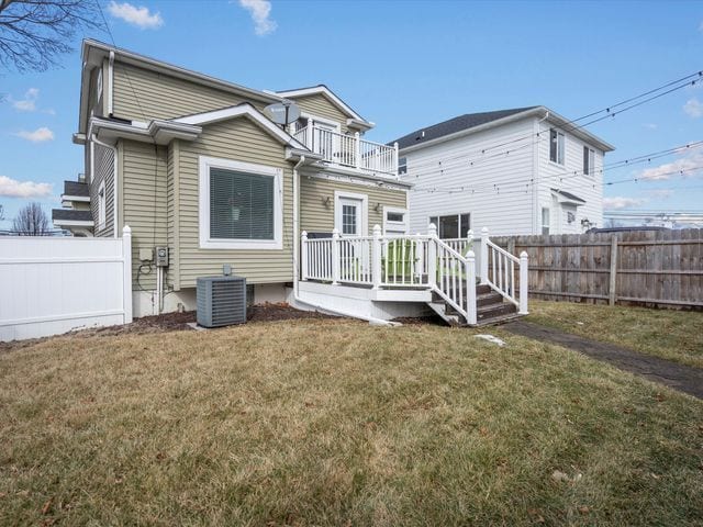 back of property with a balcony, central AC unit, and a deck