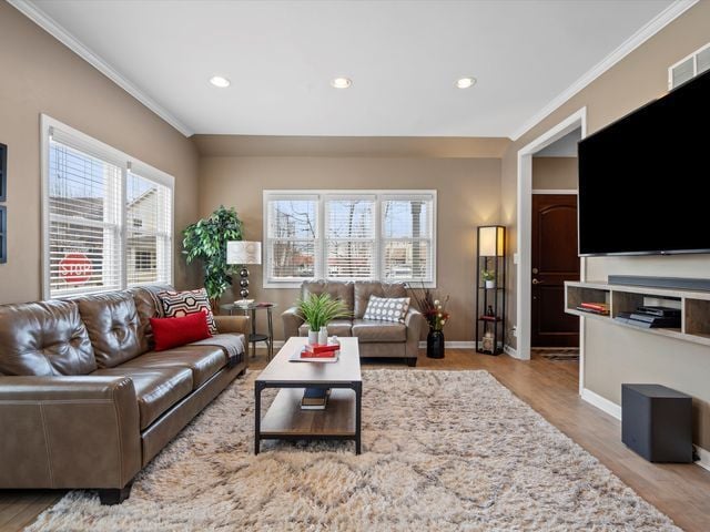 living room featuring healthy amount of natural light, ornamental molding, recessed lighting, wood finished floors, and baseboards