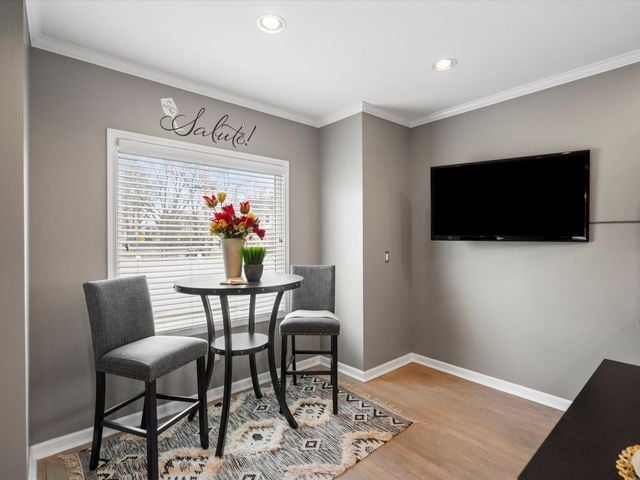 dining space with crown molding, baseboards, wood finished floors, and recessed lighting