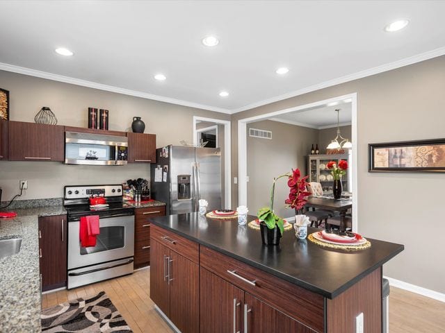 kitchen featuring stainless steel appliances, light wood finished floors, recessed lighting, a kitchen island, and ornamental molding