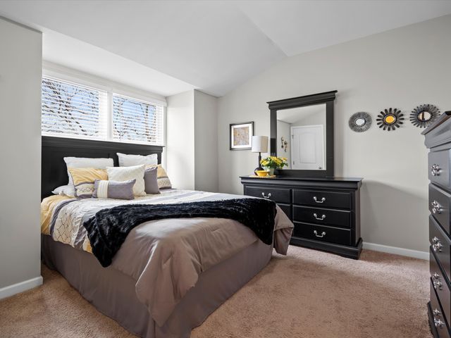 carpeted bedroom with vaulted ceiling and baseboards
