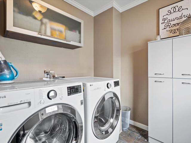 laundry area featuring cabinet space, separate washer and dryer, ornamental molding, baseboards, and dark stone finish flooring