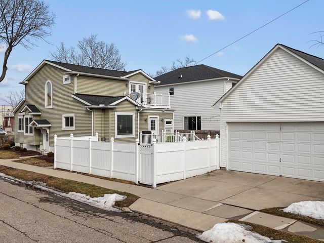 view of front of home featuring a balcony, concrete driveway, and a fenced front yard