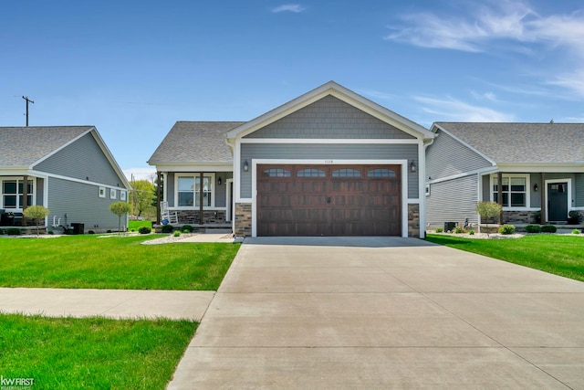 craftsman inspired home with a front yard, an attached garage, stone siding, and driveway