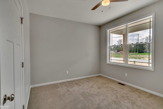 carpeted spare room with ceiling fan and baseboards