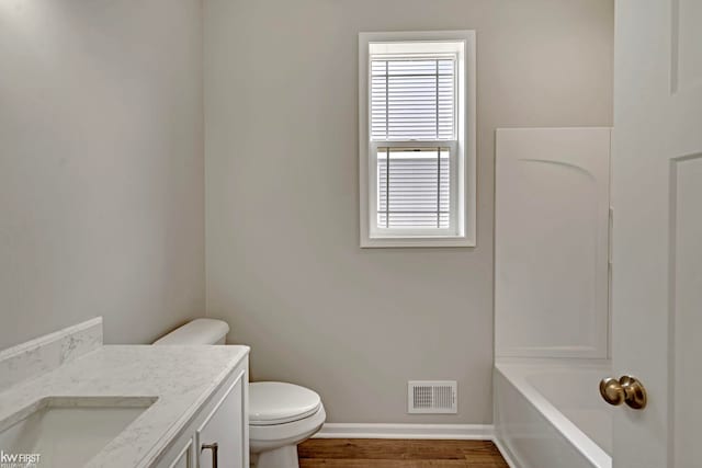 full bathroom featuring baseboards, toilet, a tub, vanity, and wood finished floors