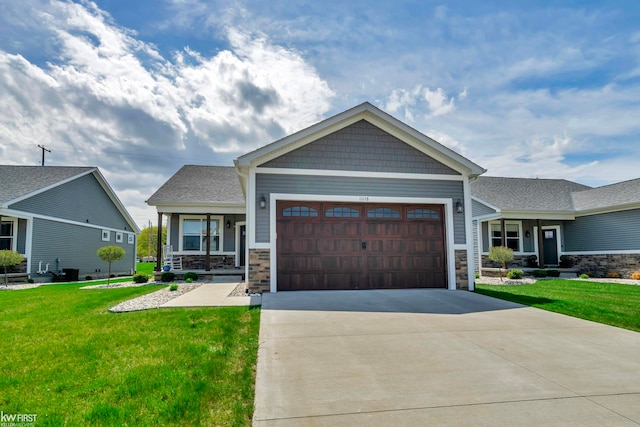 craftsman-style home with an attached garage, a front yard, concrete driveway, stone siding, and a porch