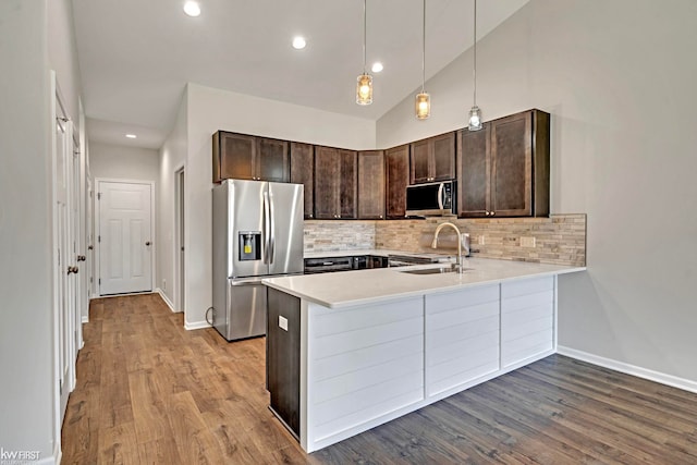 kitchen featuring stainless steel appliances, dark brown cabinets, light countertops, tasteful backsplash, and recessed lighting
