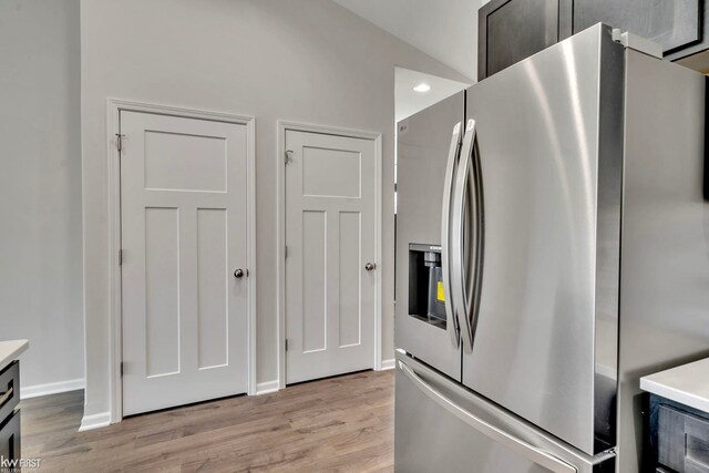 kitchen with stainless steel fridge with ice dispenser, light wood-type flooring, light countertops, and baseboards