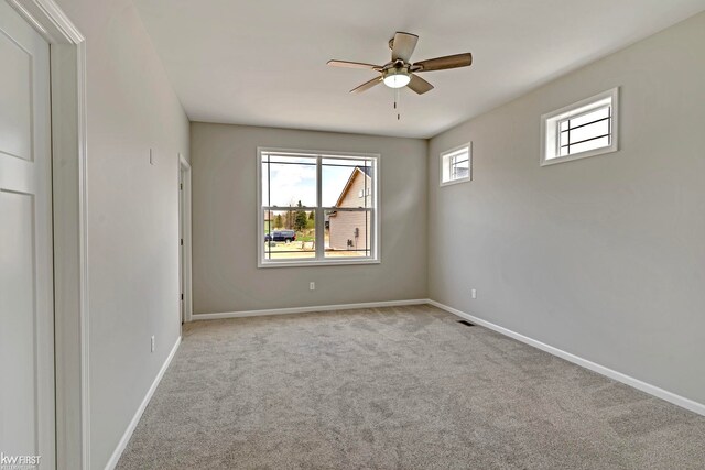 carpeted empty room with a ceiling fan and baseboards