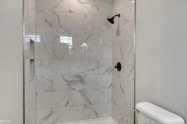 bathroom with a tile shower and toilet