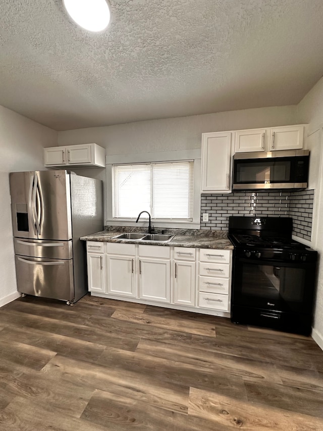 kitchen featuring stainless steel appliances, a sink, a textured ceiling, white cabinets, and decorative backsplash