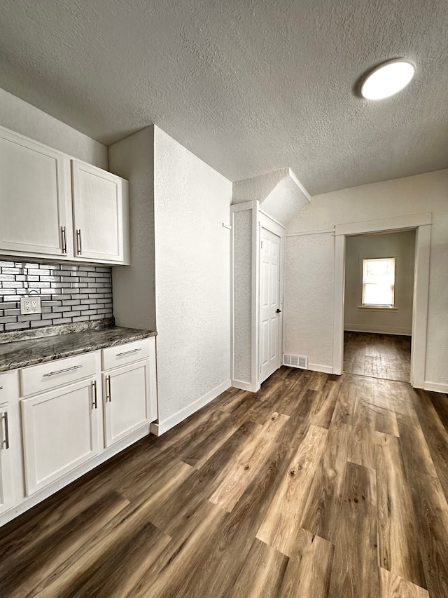 bonus room featuring a textured ceiling, dark wood-type flooring, baseboards, and lofted ceiling