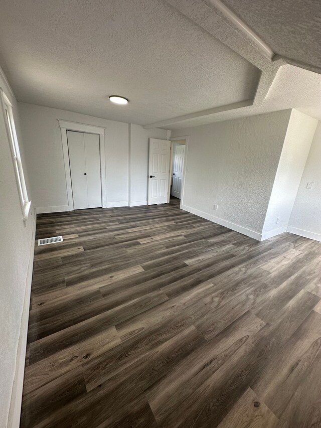 unfurnished bedroom featuring baseboards, dark wood finished floors, and a textured ceiling