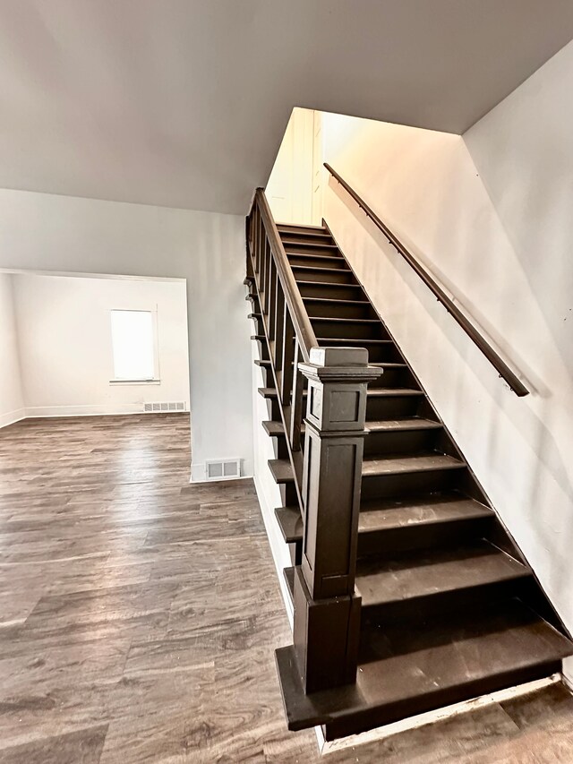 staircase featuring wood finished floors and baseboards