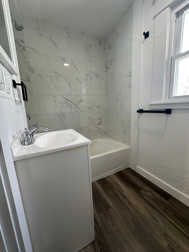 bathroom with wood finished floors, shower / tub combination, vanity, and baseboards