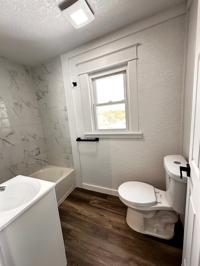 full bathroom featuring toilet, wood finished floors, a textured ceiling, vanity, and baseboards