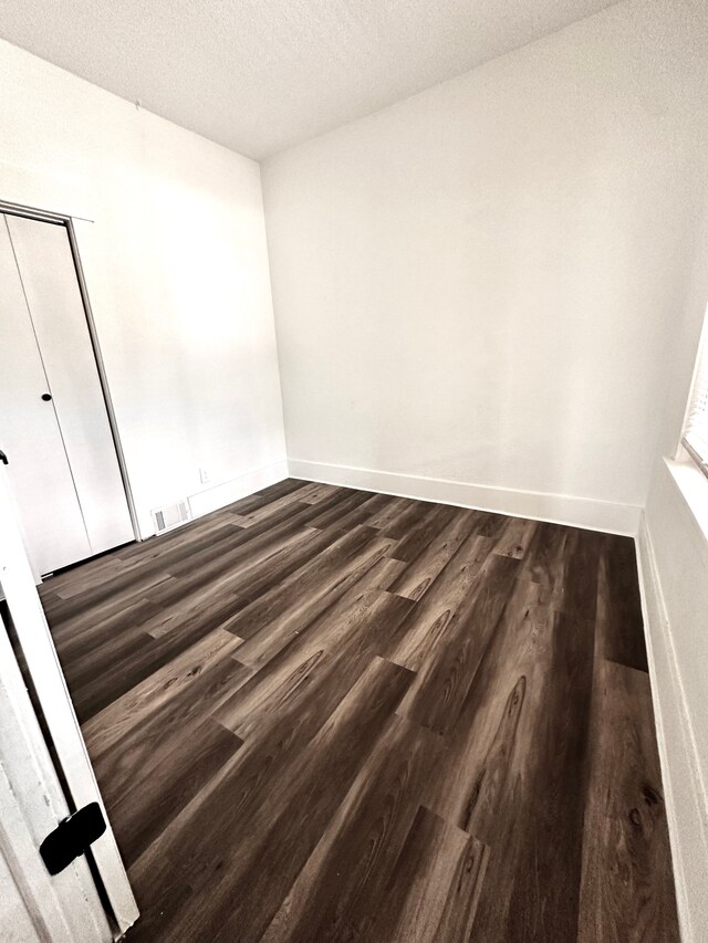 empty room featuring dark wood-style floors, baseboards, and a textured ceiling