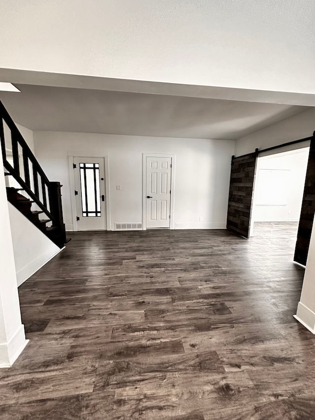 foyer with a barn door, stairway, dark wood-type flooring, and baseboards