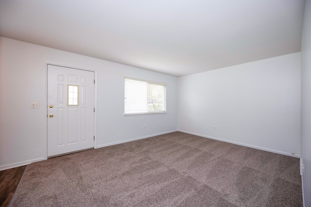 foyer entrance with baseboards and dark colored carpet