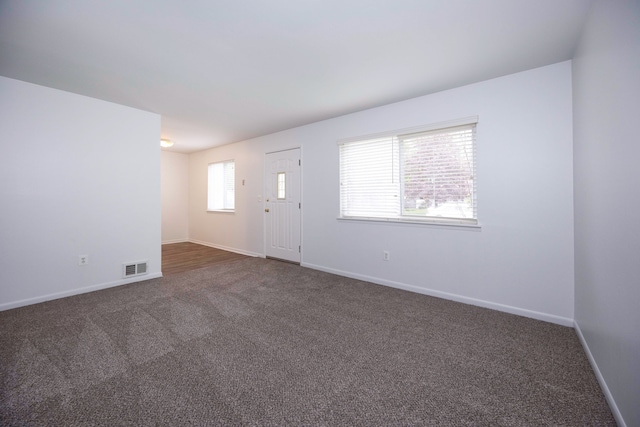 unfurnished living room featuring dark colored carpet and baseboards