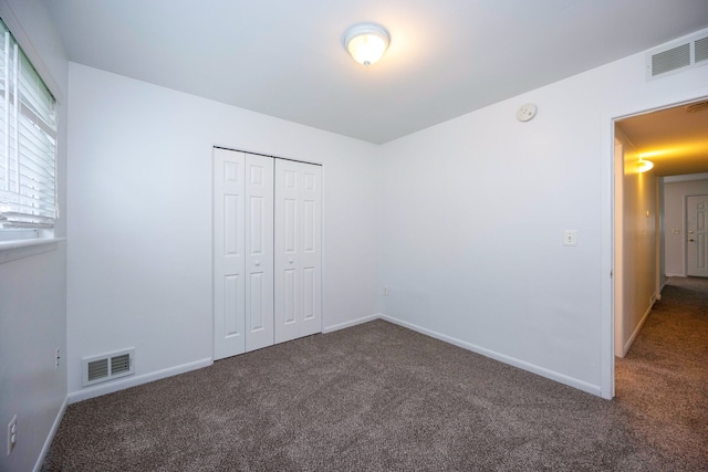 unfurnished bedroom with carpet, a closet, and baseboards