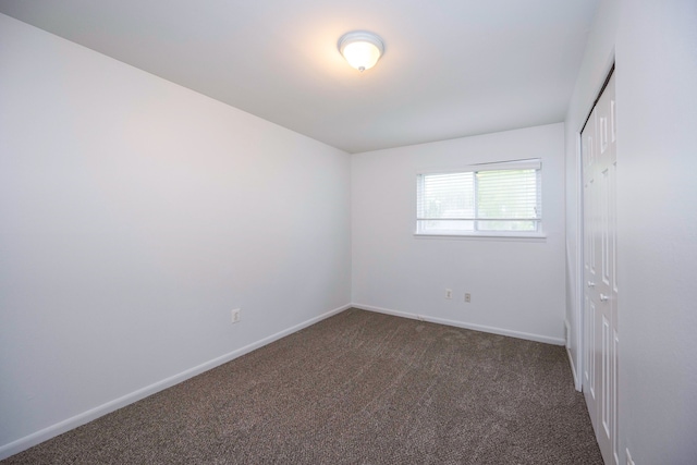 empty room with dark carpet and baseboards