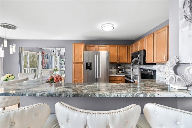 kitchen featuring appliances with stainless steel finishes, backsplash, dark stone counters, and a peninsula