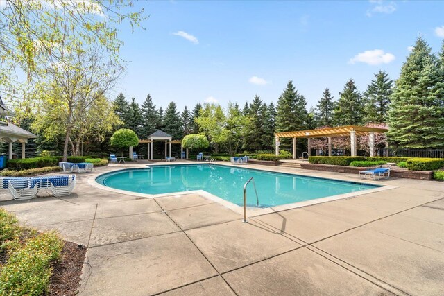 community pool featuring a patio, a pergola, a gazebo, and view of wooded area