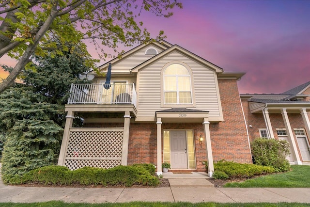 view of front facade with a balcony and brick siding