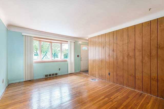 spare room with hardwood / wood-style flooring and wood walls