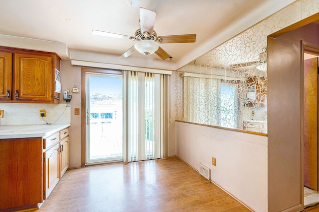 kitchen with brown cabinets, light wood finished floors, light countertops, and a ceiling fan