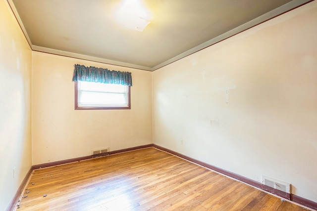 spare room with wood finished floors, ornamental molding, and baseboards