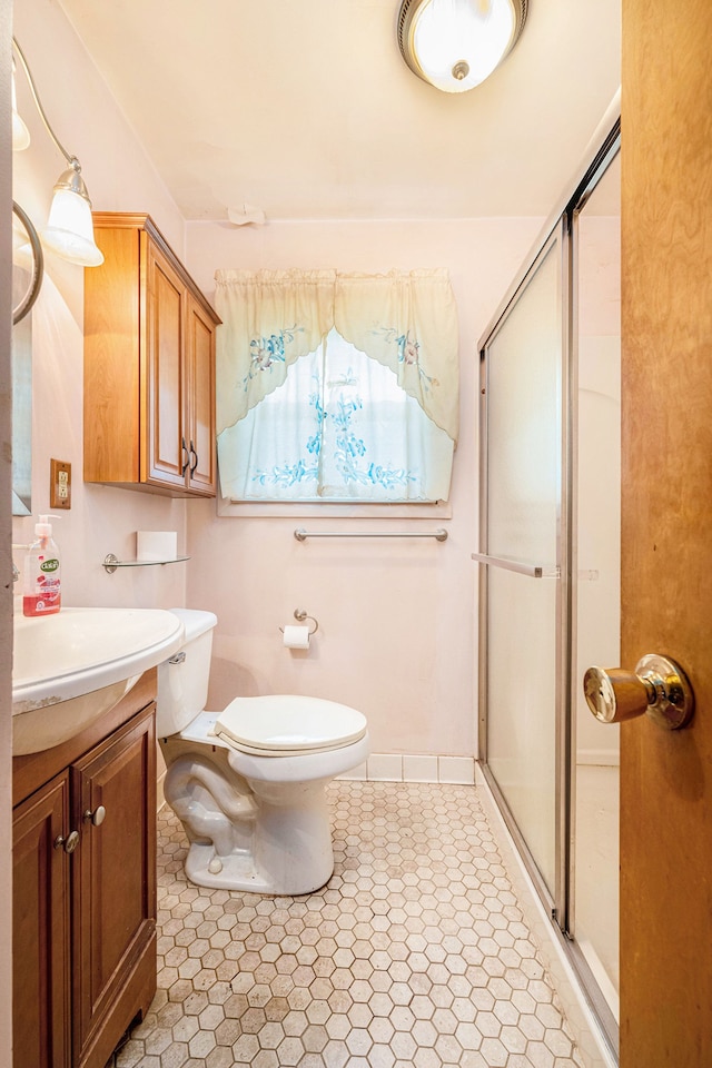 bathroom with a shower stall, vanity, toilet, and tile patterned floors