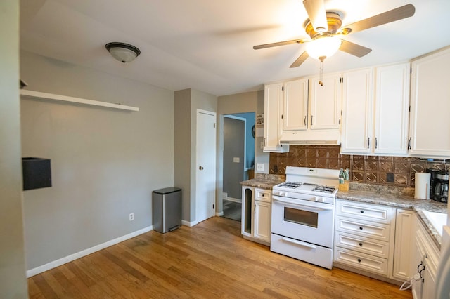 1291 103rd Ave, Plainwell, MI 49080 - kitchen with white range with gas cooktop, under cabinet range hood, backsplash, ceiling fan, and light wood-type flooring
