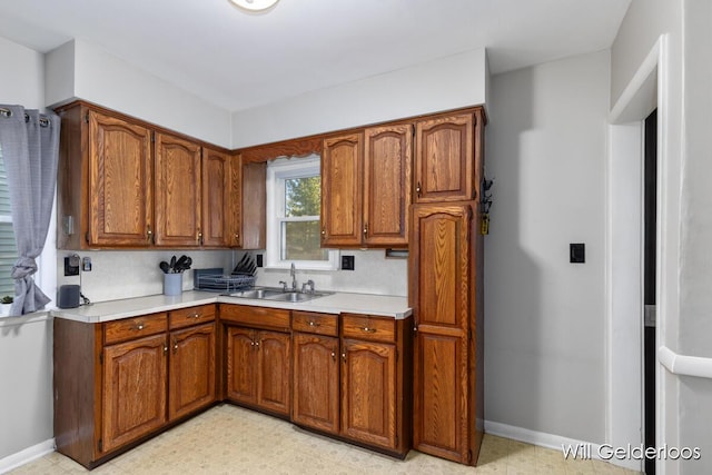 kitchen with a sink, light countertops, and brown cabinets