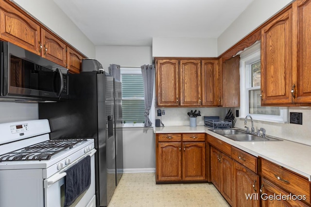kitchen with gas range gas stove, a sink, light floors, and brown cabinets