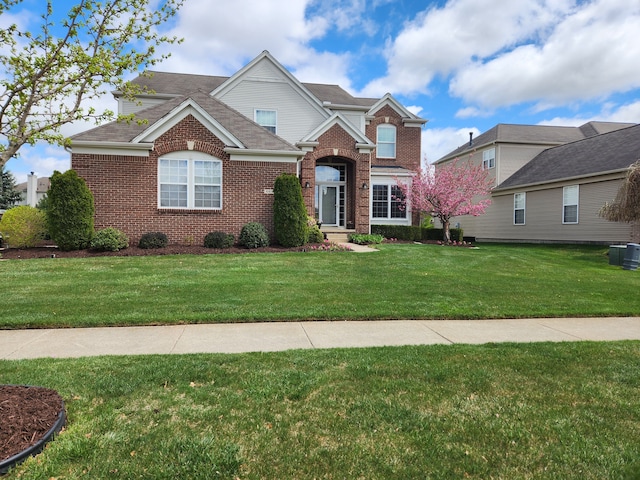 traditional home featuring brick siding, a front yard, central air condition unit, and roof with shingles