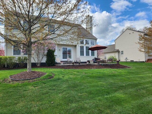 back of house with a chimney, a patio area, and a yard