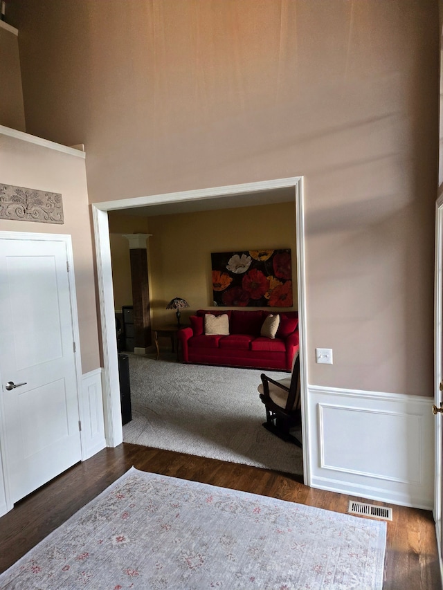 foyer with a wainscoted wall, wood finished floors, and a towering ceiling