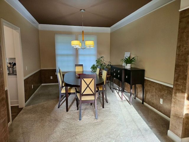 dining space with ornamental molding, a chandelier, carpet flooring, and wainscoting